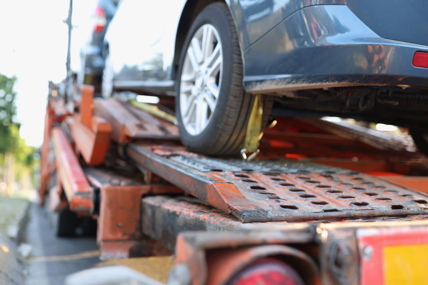 A close-up view of an automobile wheel secured on a flatbed tow truck during transport.