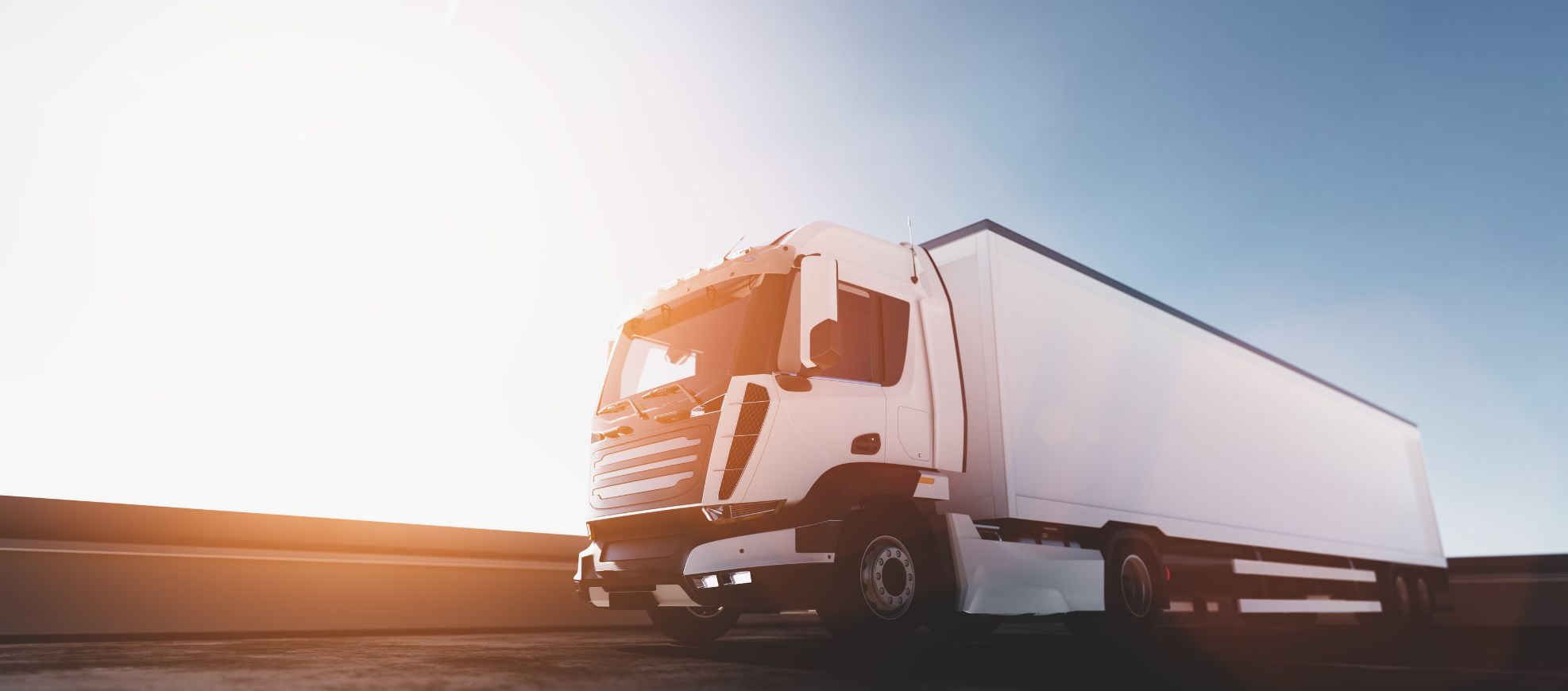 A white semi-truck is pictured driving on a highway under a clear sky with the sun shining brightly. For more details about terms and conditions, please contact us today.